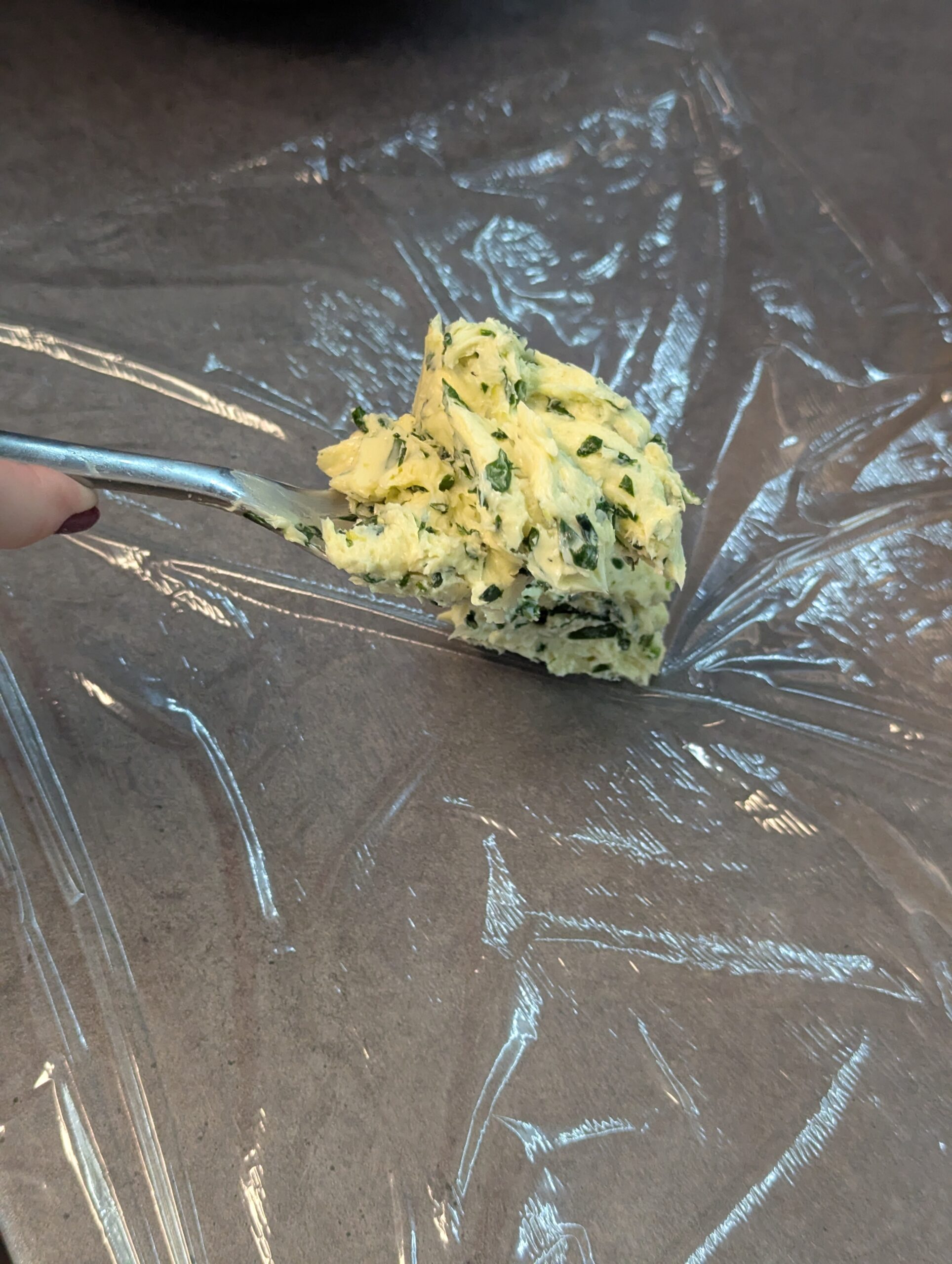 Bärlauchbutter zu einer Rolle auf Klarsichtfolie geformt